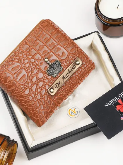 A tan crocodile leather wallet personalized with a crown charm and a 'Dr.' title.