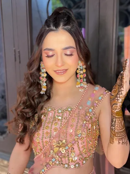 A close up on the shimmering pink eyeshadow and flawless skin for this Mehendi ceremony. The soft curls and delicate jewelry complete this beautiful daytime look.