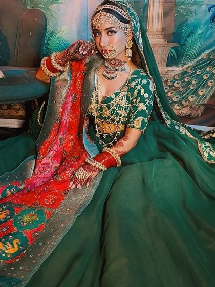 A beautiful bride in a rich green lehenga with a colorful dupatta. The makeup is kept classic and elegant to balance the vibrant outfit.