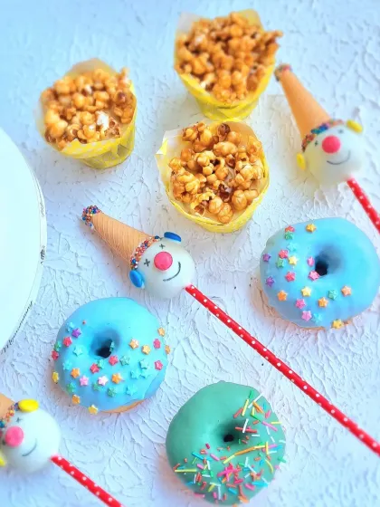 A close-up of the adorable carnival-themed treats, including donuts with sprinkles and clown cakesicles.