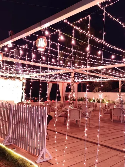 A view of an outdoor lounge area illuminated entirely by a dense canopy of fairy lights. This kind of lighting design instantly creates a magical and intimate atmosphere for guests to mingle.