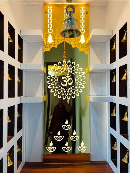 A close-up of a custom mandir, showing the detailed craftsmanship. This design features a backlit acrylic panel with an 'Om' motif, a hanging brass bell, and small niches for idols, creating a serene and beautiful prayer space.