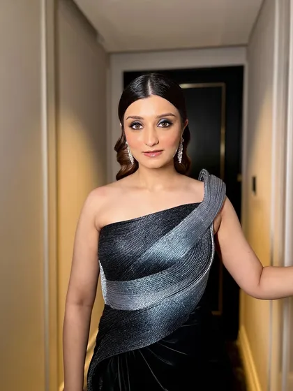 Blacked out but shining bright. This cocktail look features a dramatic winged eyeliner and glowing skin, paired with a stunning black and silver one-shoulder gown.