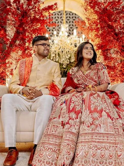 The couple seated on their elegant reception stage, a perfect picture of modern romance with the bold red and white decor.