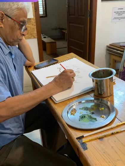 An elderly student practices his watercolor techniques. Our classes are for everyone, proving that it's never too late to pursue a passion for art.