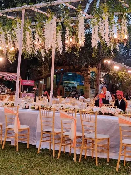 For this rustic outdoor reception, we designed a long head table under a canopy of hanging white wisteria and Edison bulbs. This created an intimate and magical dining experience for the wedding party.