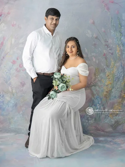 A classic seated portrait of the couple. The floral bouquet adds a lovely detail, and their relaxed posture shows their comfort and connection.