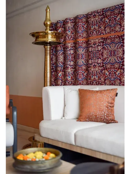 The living room is a harmonious blend of tradition and modernity, with the brass diya and Kalamkari fabric creating a strong cultural statement.