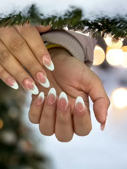 A winter-themed French manicure with soft white tips and a subtle glitter fade. This elegant look is perfect for the holiday season or a sophisticated winter style.