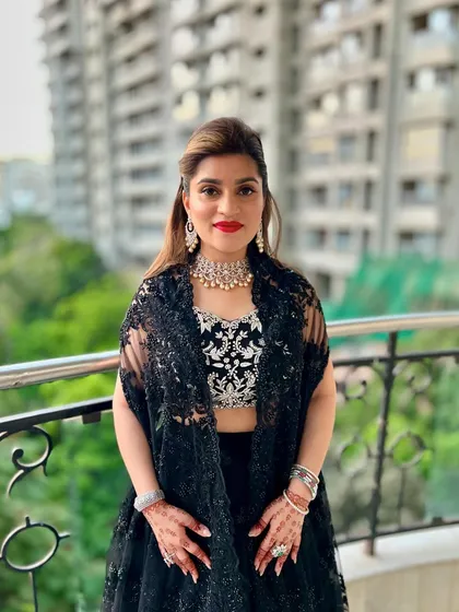 A full view of the client ready for her event. The half-up hairstyle with the black bow and bold red lip creates a striking and confident look.