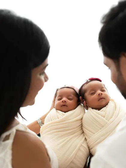 An over-the-shoulder view showing the parents looking down at their two precious babies. A beautiful perspective on a new family of four.