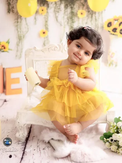 Before the cake, we capture timeless portraits. Here, a beautiful baby girl shines in our popular sunflower-themed set, complete with a matching yellow dress.