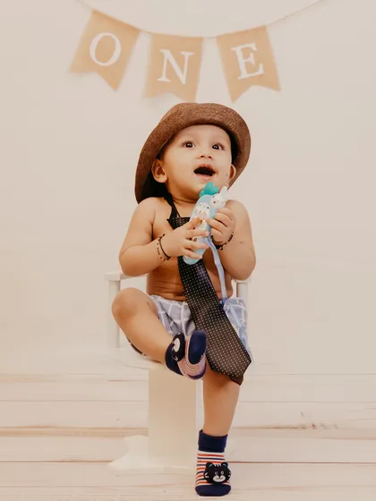 An energetic and happy shot of a one-year-old boy, captured mid-laugh during his studio birthday session.
