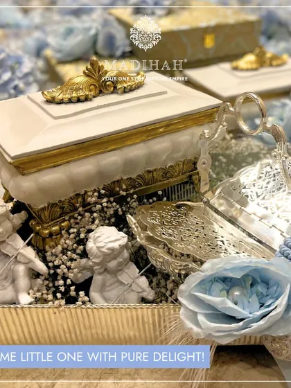 "Welcome little one with pure delight!" This baby announcement hamper features cherub figurines, a silver-plated shell dish, and an ornate box, all in a beautiful blue and white color scheme for a baby boy.