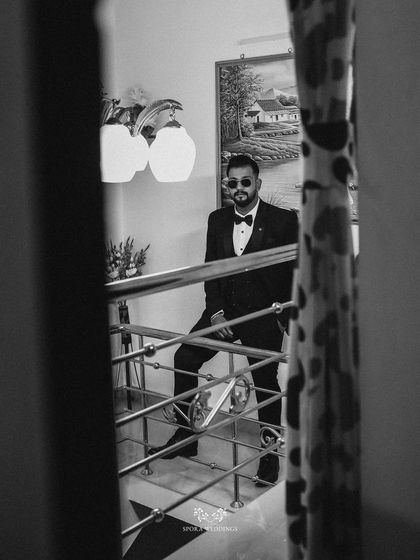 A black and white portrait of the groom looking cool and confident on the stairs, a mirror reflection adding an artistic touch.