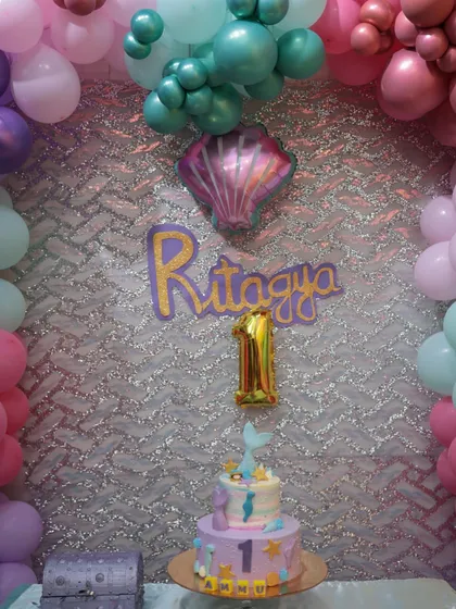 The centerpiece of a first birthday mermaid party. The custom name cutout, number '1' balloon, and themed cake come together to create a perfect spot for photos.