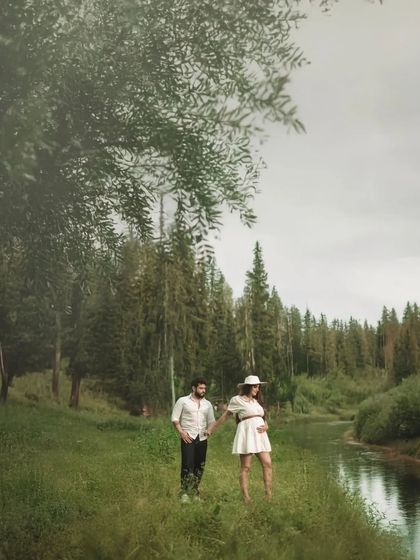 A candid shot of the couple walking by the river, their connection evident in their shared path. The moody, natural lighting adds a cinematic quality to the image.