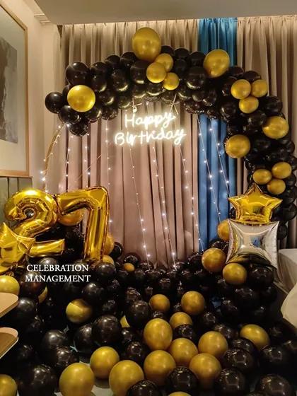 Here’s a stylish and modern setup for a 27th birthday. I designed a full circular arch with black and gold balloons, a 'Happy Birthday' neon sign, and large foil balloons for the age, creating a perfect spot for birthday photos.