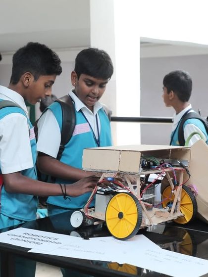Two students collaborate on their robot, making final adjustments before a competition. This image captures the focus and teamwork we foster in our classes.