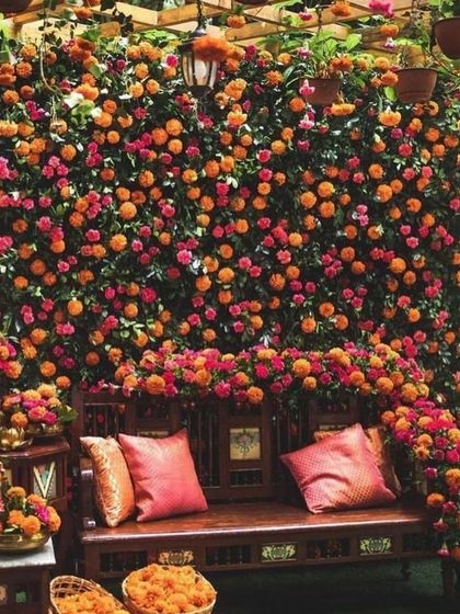 A dense wall of orange and pink marigolds creates a stunningly vibrant and traditional backdrop for the Haldi ceremony seating.