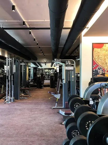 A view down the line of weight machines and dumbbell racks. The organization of the equipment was carefully planned to ensure a smooth and efficient workout flow.