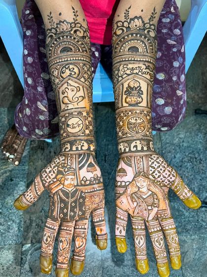 This custom bridal design features portraits of the couple, the names 'Sagar' and 'Mansi', a Ganesha motif for blessings, and other personal symbols.
