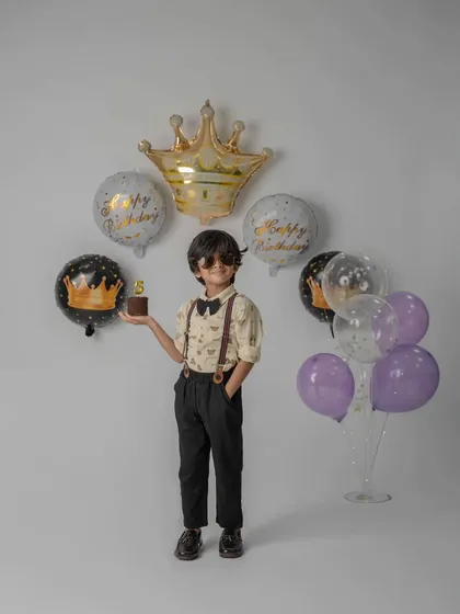 This young man is ready to celebrate his 5th birthday in style. I use props like crown balloons and a mini cake to add a special touch to milestone photos.