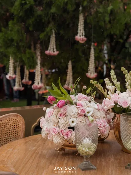 A beautiful centerpiece of pink and white roses, with traditional floral strings hanging in the background, blending modern and classic decor elements seamlessly.