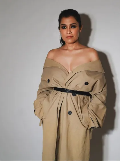 A modern, stylish portrait from a birthday celebration. The off-the-shoulder trench coat creates a chic and powerful look.