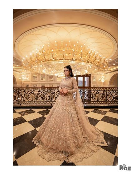 A breathtaking solo portrait of the bride in a grand ballroom. The massive chandelier and checkered floor create a sense of opulence and high fashion for her engagement look.