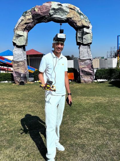 Posing with a small FPV drone, ready to fly through a racing gate. This shows the fun and sporty side of drone flying.