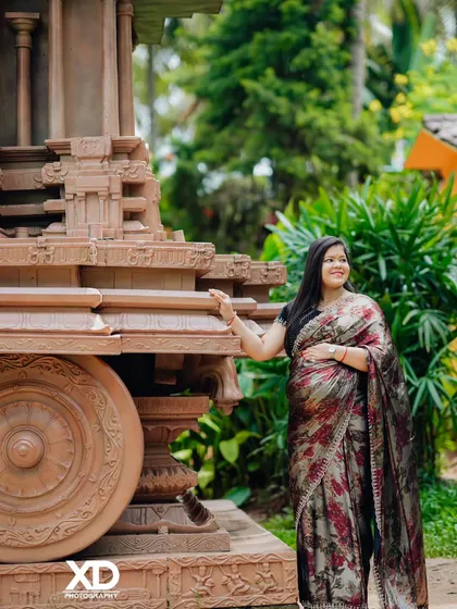 A smiling portrait of the mother-to-be next to the stone chariot, her happiness radiating in the natural outdoor light.
