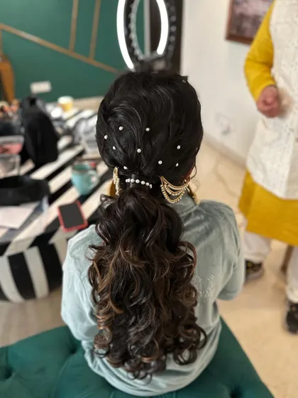 A close-up of the accessories on the messy ponytail, combining modern pearls with traditional gold jewelry.