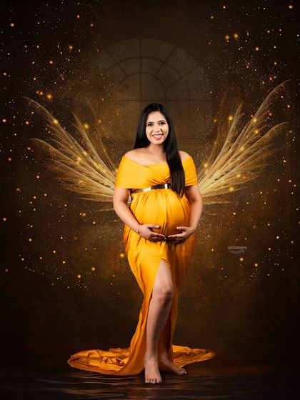 A magical, angelic portrait created with special effects. The client, in a flowing yellow gown, is given glowing wings against a dark, sparkling backdrop for a truly fantastical image.