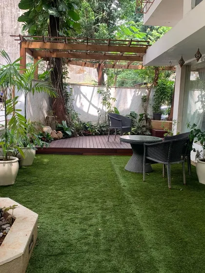Even ground-floor spaces can become serene backyard getaways. Here, we combined a manicured lawn with a shaded wooden deck and pergola, surrounded by greenery to create a perfect spot for relaxing or entertaining.