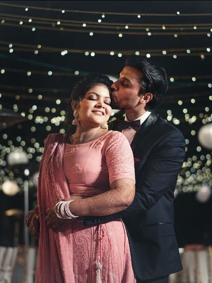 A tender kiss on the cheek under a sky of twinkling lights. This is a classic romantic shot from their wedding reception.