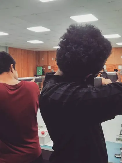 A view from behind the firing line shows two shooters in position. Our 10-meter range provides a clear and consistent environment for practice.