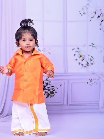 A little boy in a traditional South Indian dhoti and shirt, looking absolutely adorable.
