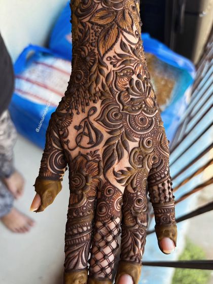 A close up of the initial 'A' woven into a very dense and intricate full hand design. The personalization becomes a seamless part of the art.