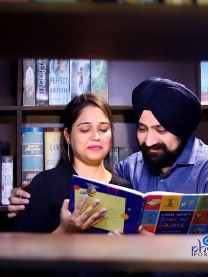 A candid moment of the couple sharing a book in the library set. This type of shot adds a layer of storytelling to the pre-wedding album.