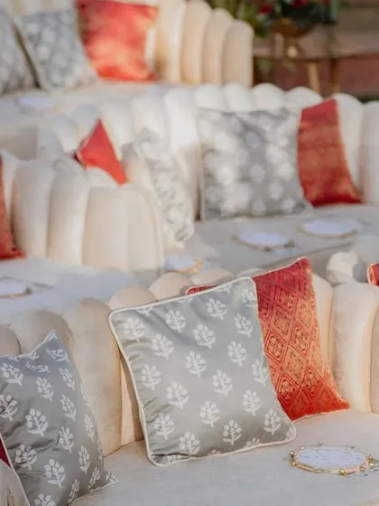 Custom cushions in shades of red, grey, and cream for the amphitheater seating at the 'Regal Rustic Reverie' wedding. These details added comfort and a touch of regal elegance.