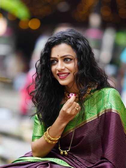 A candid portrait of a woman in a beautiful saree, smiling during an outdoor shoot. Her joy and elegance are perfectly captured.