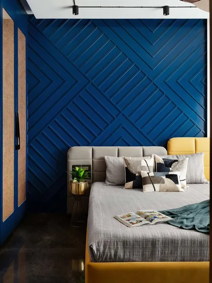 The combination of the bold blue wall, yellow bed frame, and patterned cushions creates a bedroom full of personality and style. It’s a space designed to be both energetic and restful.
