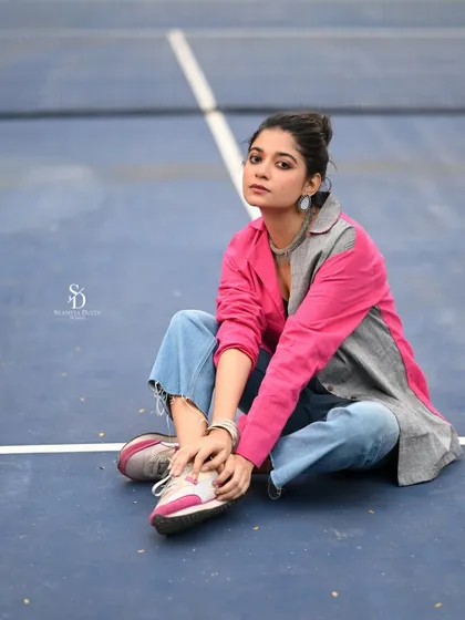 A seated portrait on the court, allowing for a closer look at the casual styling with sneakers and ripped jeans.