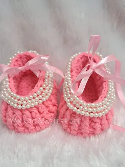 A close-up of the pink pearl booties, showing the detail of the pearls and the soft pink ribbon.