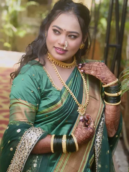 A beautiful bride in her green wedding saree. The makeup is soft and glowing, paired with traditional gold jewellery and a classic Maharashtrian nath.