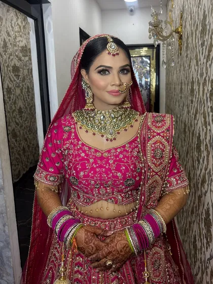 A full-length shot capturing the grandeur of the bridal look. The makeup is designed to be impactful yet not overpowering, balancing the heavily embroidered lehenga and jewellery.