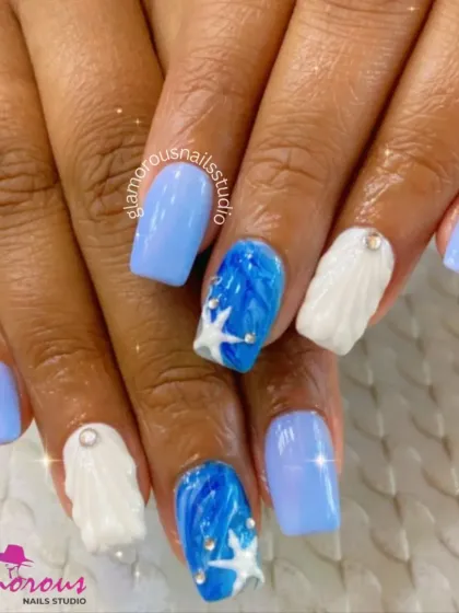 Get ready for a beach vacation with these ocean-themed nails. We combined shades of blue and white, creating a 3D wave and shell texture on some nails and adding tiny starfish and rhinestones for a complete seaside vibe.