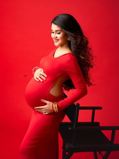 This side-profile shot highlights the beautiful cut of the open-back red gown and the gorgeous baby bump. It's a mix of elegance and allure.