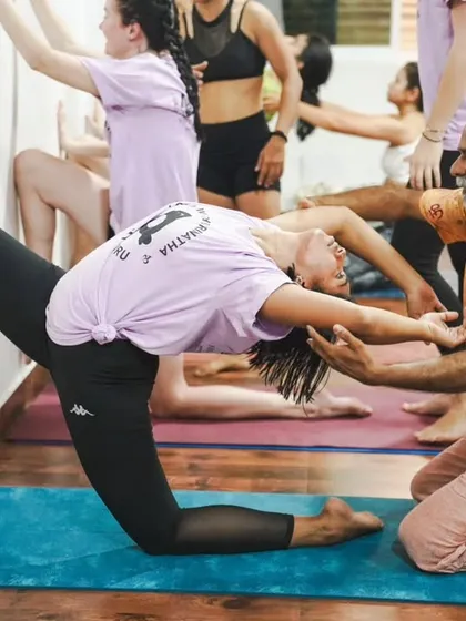 I am assisting a student in a kneeling backbend against the wall, a safe and effective way to open the heart and shoulders.